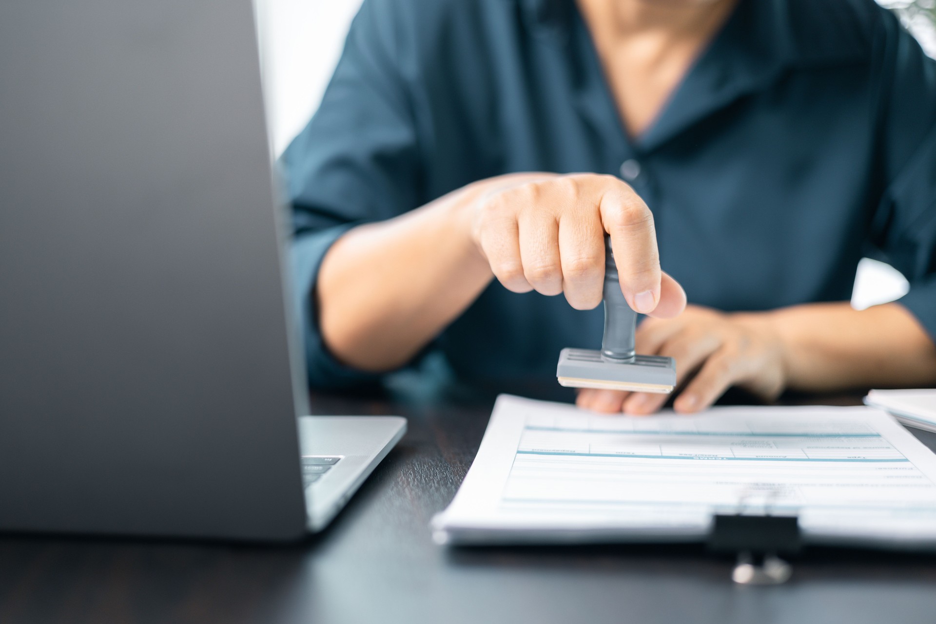 Banking officer stamped the document to approve the loan, finalizing the contract and solidifying the finance agreement, fundamental concept in business transactions. approve, loan, stamp, business.