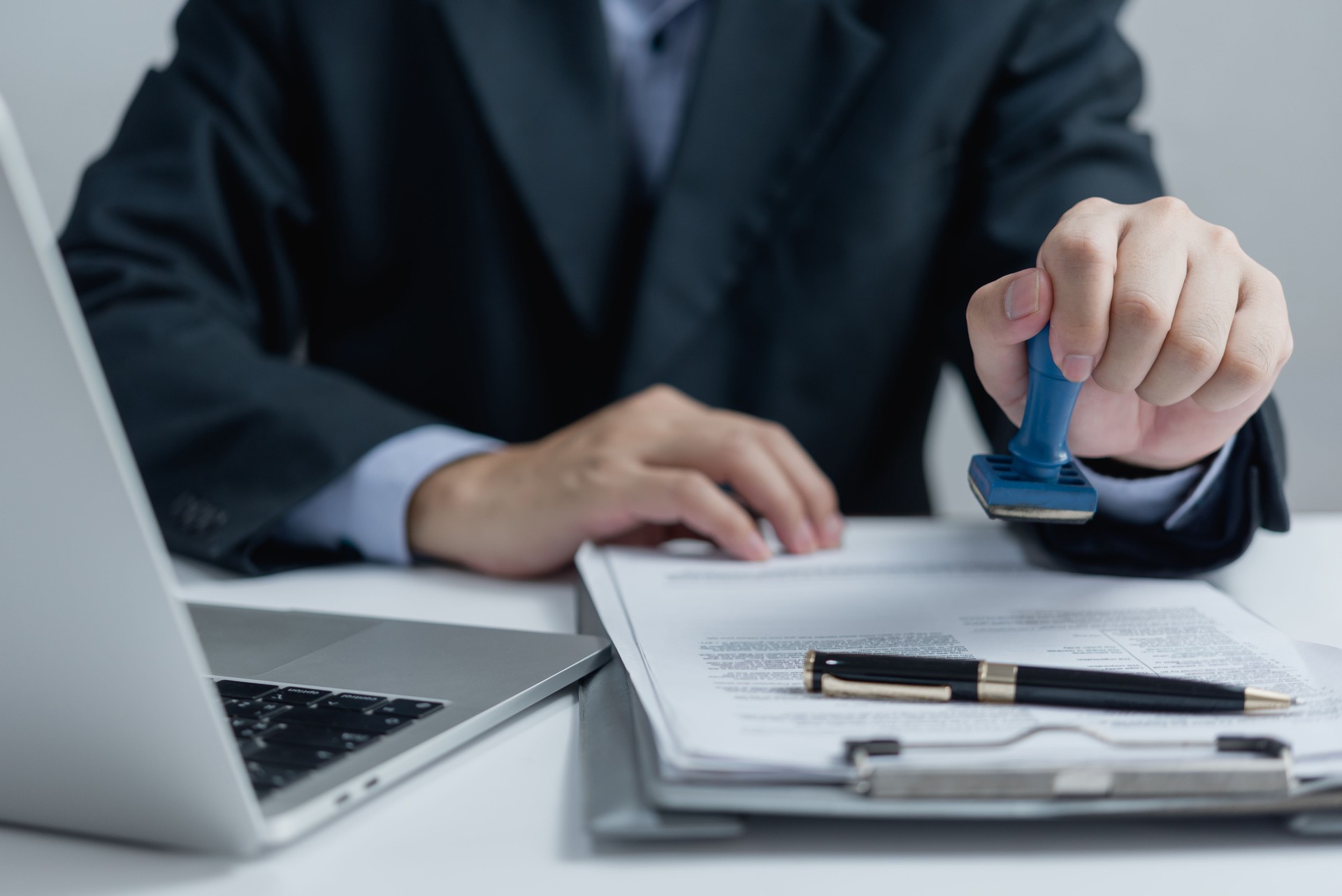 Man stamping approval of work finance banking or investment marketing documents on desk.
